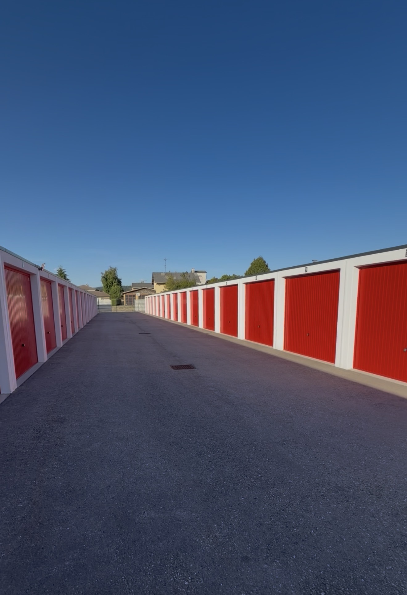Spacebox Garagenbox mit rotem Tor in Mattighofen, davor ein Pkw mit Anhänger